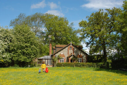 Venkovský dům v krajině s loukou a vzrostlými stromy