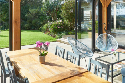 Prosklená terasa venkovského domu s dřevěným nábytkem a výhledem do zahrady
