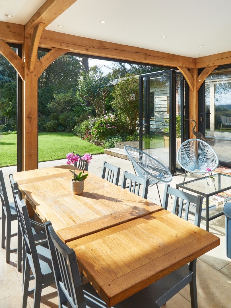 Prosklená terasa venkovského domu s dřevěným nábytkem a výhledem do zahrady