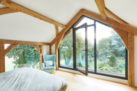 Ložnice s dřevěnými trámy a panoramatickým oknem