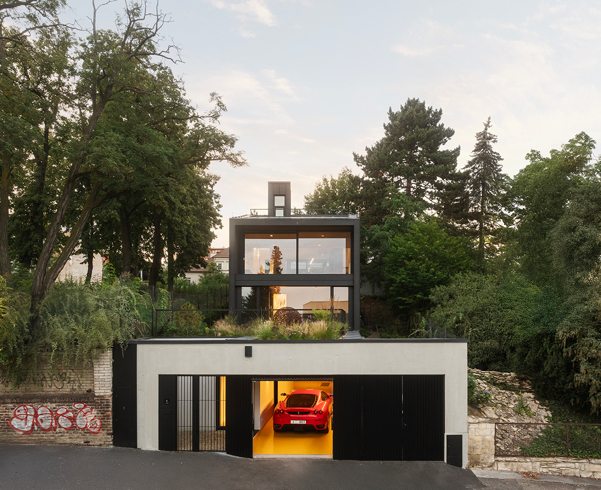 Pohled na rodinný dům Black House v Praze s terasou, zelení a integrovanou garáží