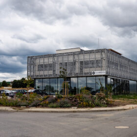 Moderní administrativní budova Narran s proskleným přízemím a kovovou fasádní strukturou.