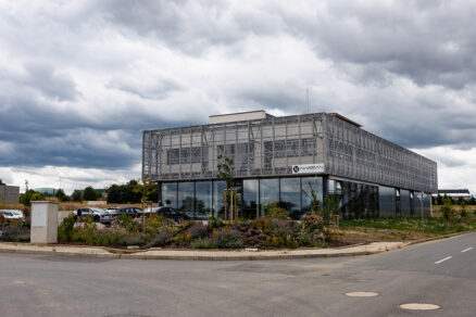 Moderní administrativní budova Narran s proskleným přízemím a kovovou fasádní strukturou.