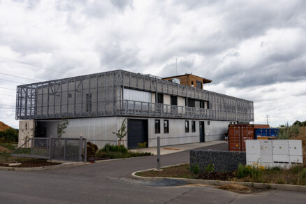 Moderní kancelářská budova s perforovaným obvodovým pláštěm a technickým zázemím.