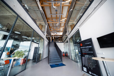 Interiér administrativní budovy Narran s otevřeným atriem, schodištěm a prosklenými kancelářemi.