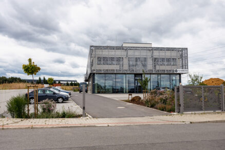 Moderní kancelářská budova s perforovaným obvodovým pláštěm a technickým zázemím.