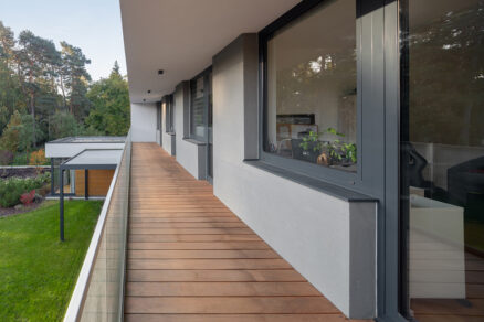 Balkon rodinného domu s hliníkovými okny a výhledem do lesní zahrady