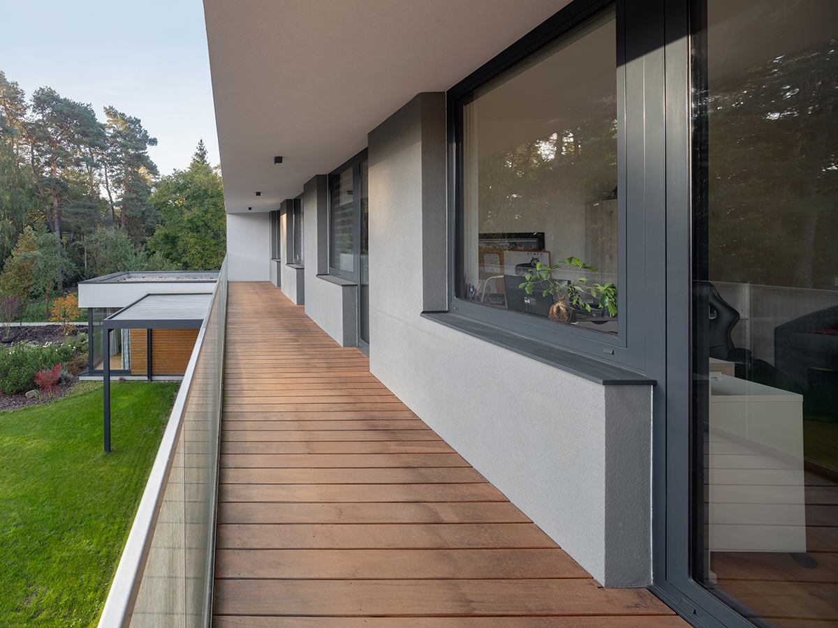 Balkon rodinného domu s hliníkovými okny a výhledem do lesní zahrady