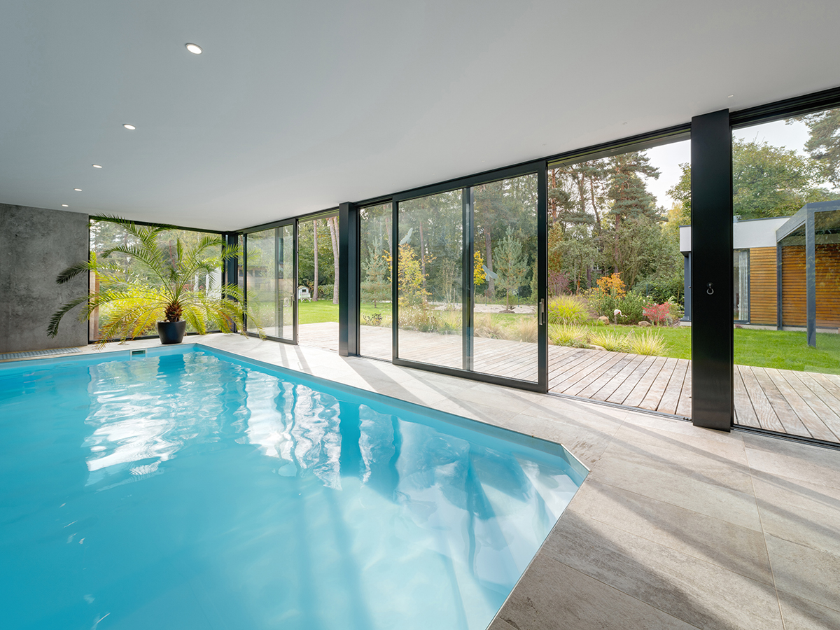 Interiérový bazén s velkoformátovými hliníkovými okny propojený se zahradou