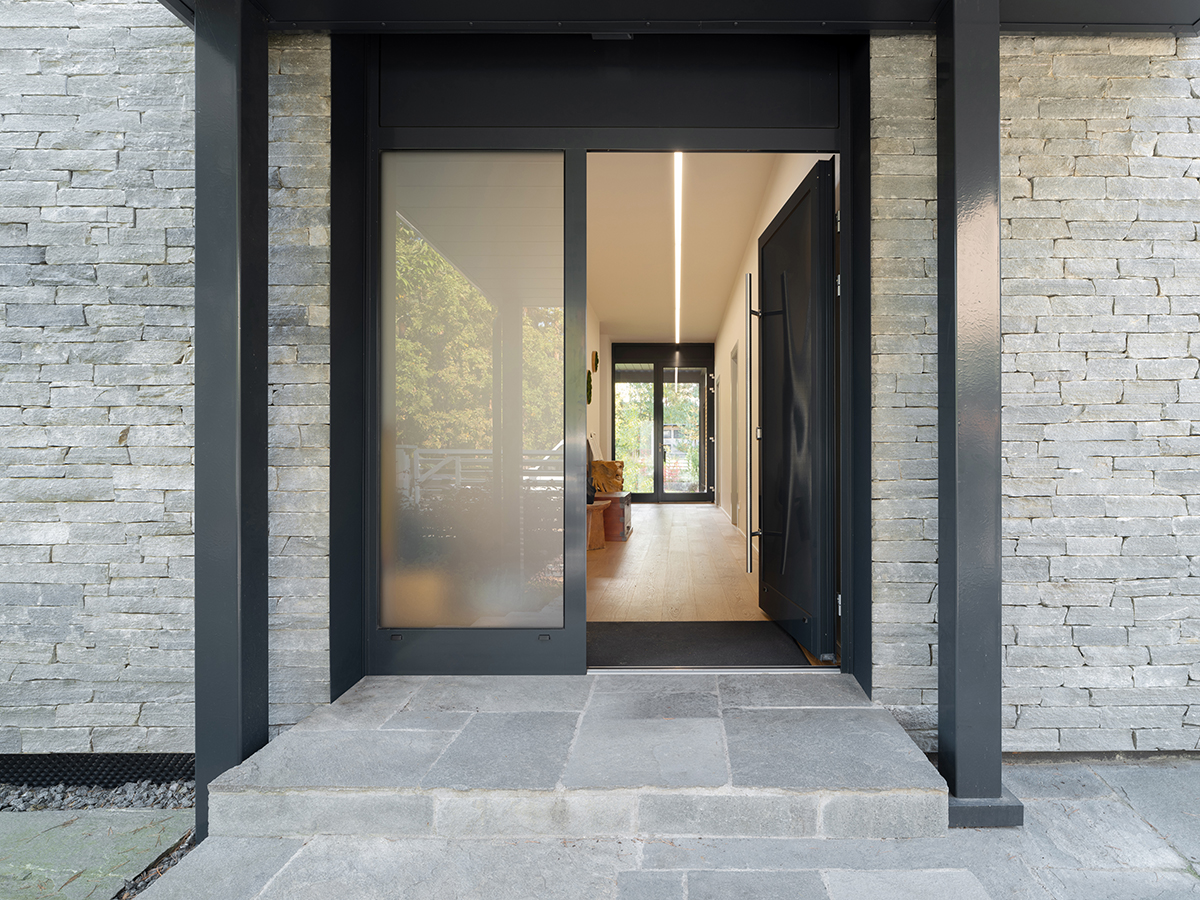 Hliníkové vstupní dveře rodinného domu s proskleným světlíkem a kamenným obkladem fasády