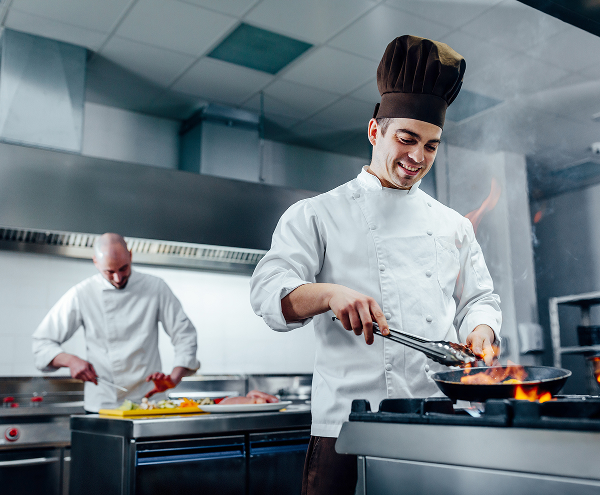 Profesionální kuchyně s akustickým podhledem a kuchaři při práci