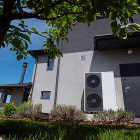 Venkovní jednotka tepelného čerpadla u moderního rodinného domu