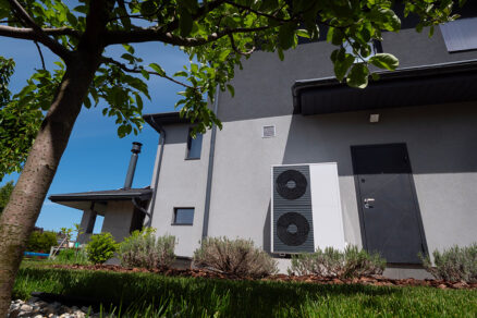 Venkovní jednotka tepelného čerpadla u moderního rodinného domu