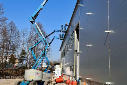 Montáž fasádních panelů na průmyslové hale pomocí plošiny