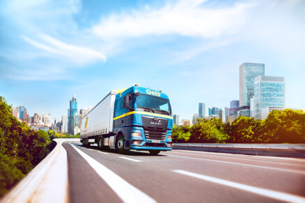 nákladné vozidlo prechádzajúce mestom s modernou infraštruktúrou