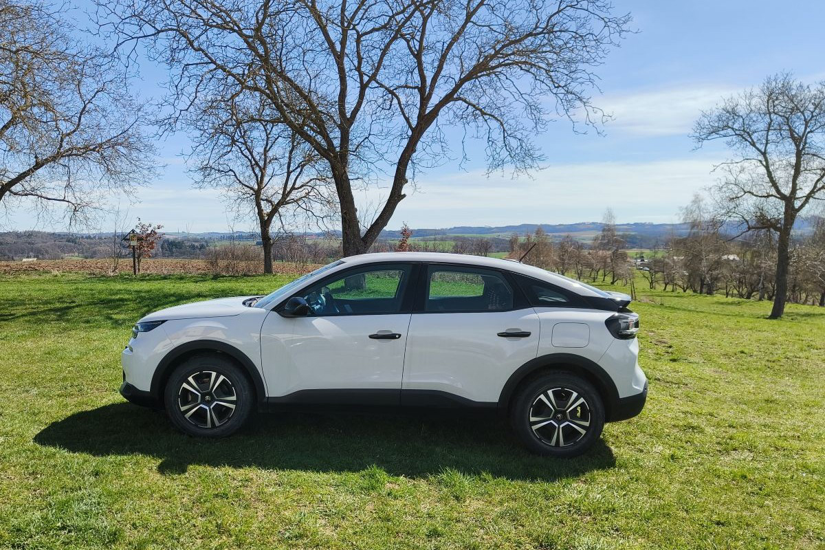 Bočný pohľad na biely Citroën C4 zaparkovaný v prírode na trávnatej ploche