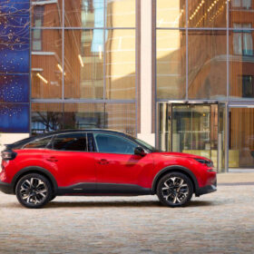 Červený Citroën C4 v mestskom prostredí pred modernou budovou, bočný profil vozidla