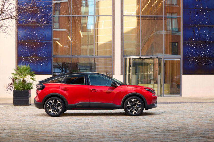 Červený Citroën C4 v mestskom prostredí pred modernou budovou, bočný profil vozidla