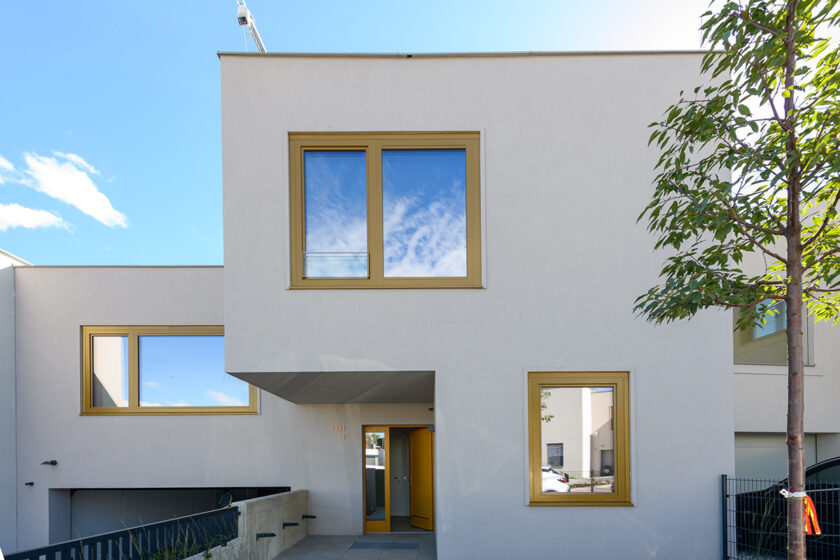 Moderní rodinný dům s kreativní fasádní omítkou a hladkým světlým povrchem.