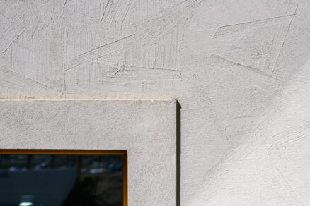Detail okenního ostění s kombinací hladké a strukturované kreativní fasádní omítky.