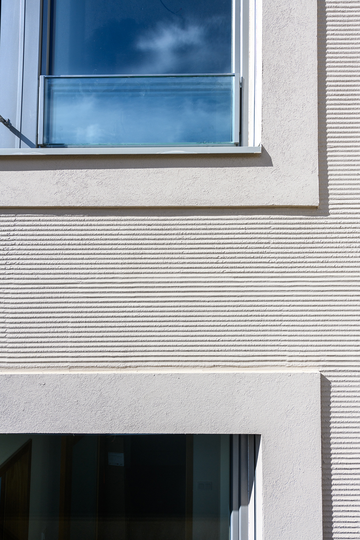Detail okenního ostění s kombinací hladké a strukturované kreativní fasádní omítky.