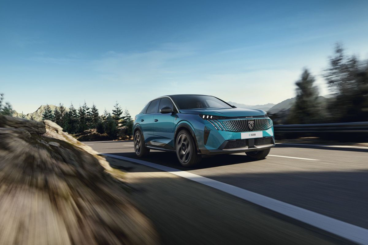 Elektrický Peugeot E 3008 při jízdě na silnici v horské krajině s důrazem na design a aerodynamiku vozu.