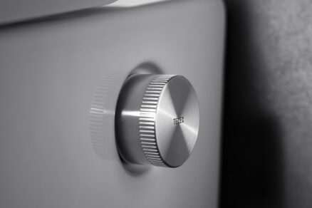 Detail mechanického ovládání sprchovací toalety s elegantním kovovým regulátorem.
