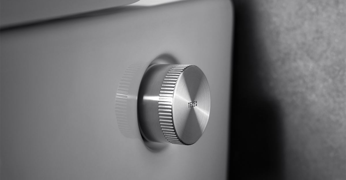 Detail mechanického ovládání sprchovací toalety s elegantním kovovým regulátorem.