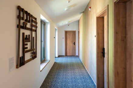 Chodba hotelu Bronzo s dřevěnými dveřmi a uměleckým dílem na stěně