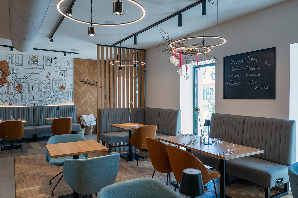 Interiér kavárny hotelu Bronzo s designovým osvětlením a čalouněnými lavicemi