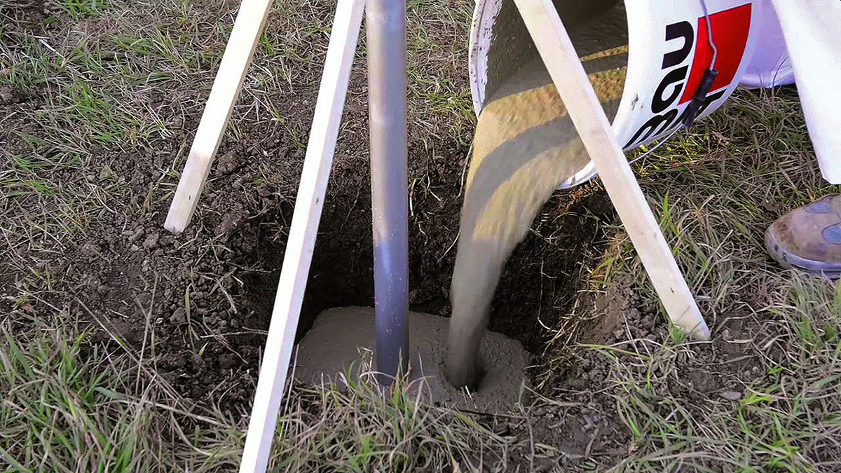 Nalévání betonové směsi do otvoru pro kotvení sloupku.
