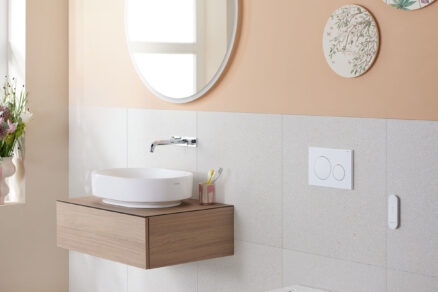 Sprchovací WC Geberit AquaClean Alba v koupelně s umyvadlem a kulatým zrcadlem