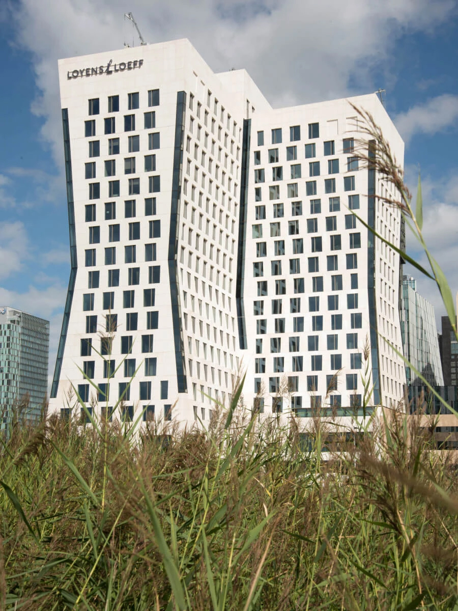 The Link, Antverpy: Moderní budova s rozsáhlými prosklenými plochami a hliníkovou fasádní konstrukcí. Hourglass, Amsterdam: Administrativní budova Hourglass s výraznou bílou fasádou a pravidelným rastrem oken.