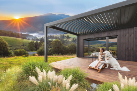 Pergola: Hliníková pergola s lamelovou střechou vytváří zastřešený venkovní prostor u rodinného domu.