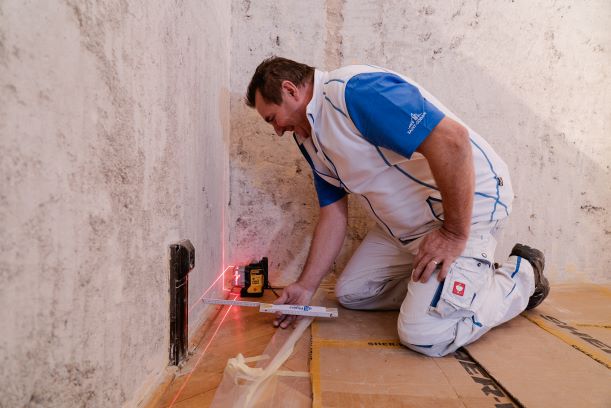 Příprava - Na podlaze si vyměříme polohu obvodového profilu R-UD. Značkovací šňůrou, tzv. „brnkačkou“, si na podlaze vytyčíme polohu obvodového R-UD profilu.