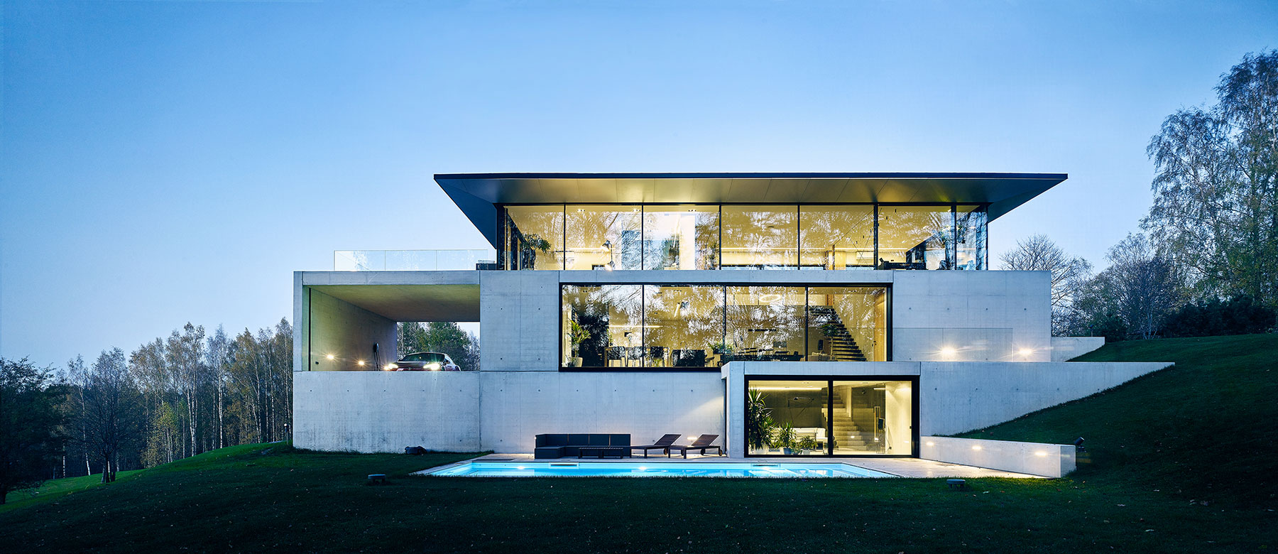Architekti studia OUTOFBOX tomu říkají "asketický design". Impozantní budova ze skla a betonu organicky zapadá do terasovitého terénu.