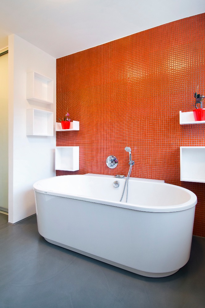V koupelně doplňují oranžové stěny s drobnou mozaikou