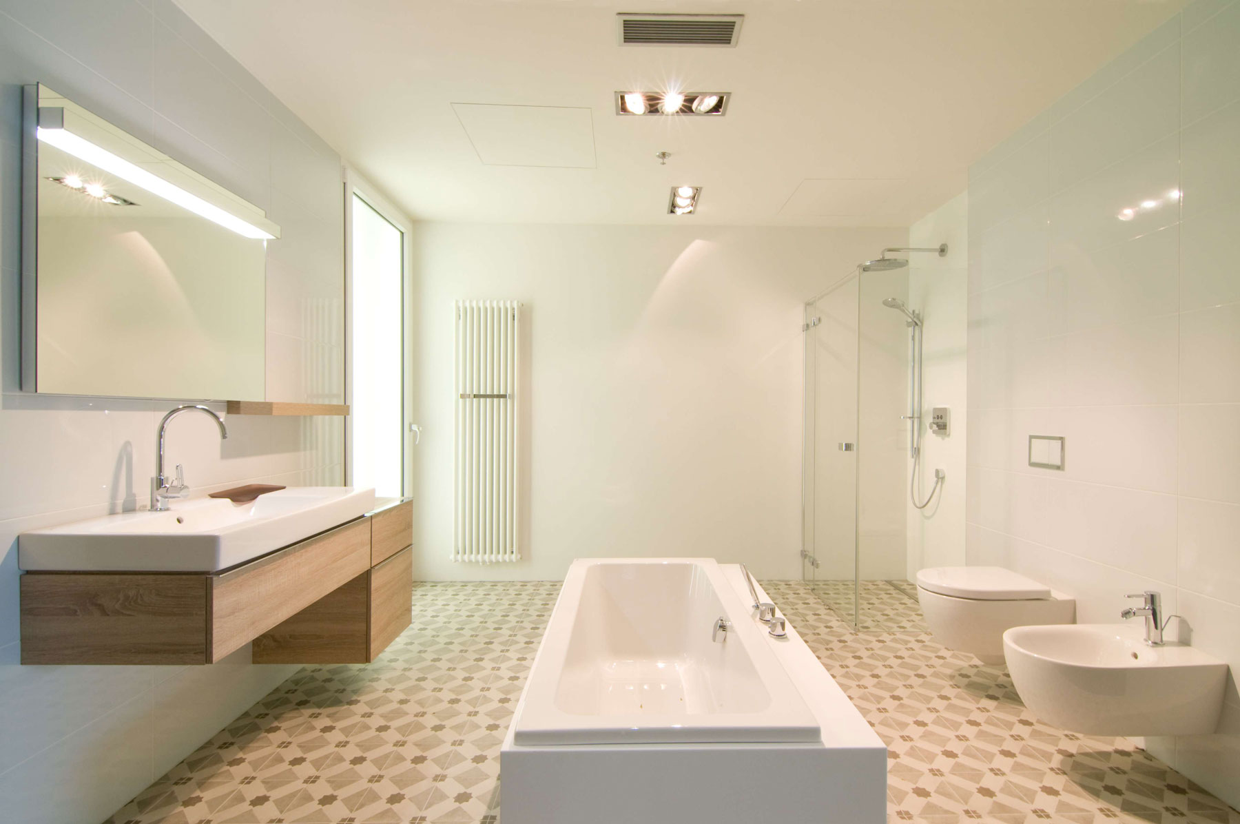 Popis: Útulná a prostorná zároveň, koupelna z řady KERAMAG iCon s volně stojící vanou MODO, dřevěným dekorem světlý dub a vkusně zalícovaným tlačítkem Geberit Omega60.