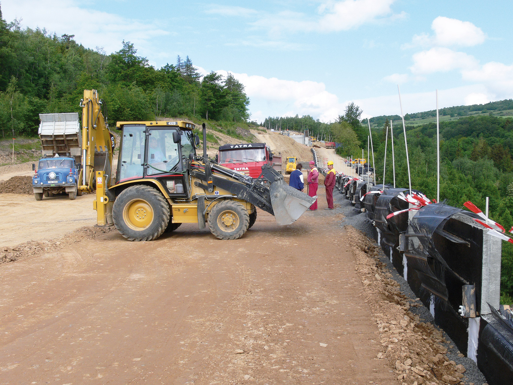 Obr. 6 Vysypávání prostoru drenážního komínu a humózní zemina za lícem strmého zeleného svahu