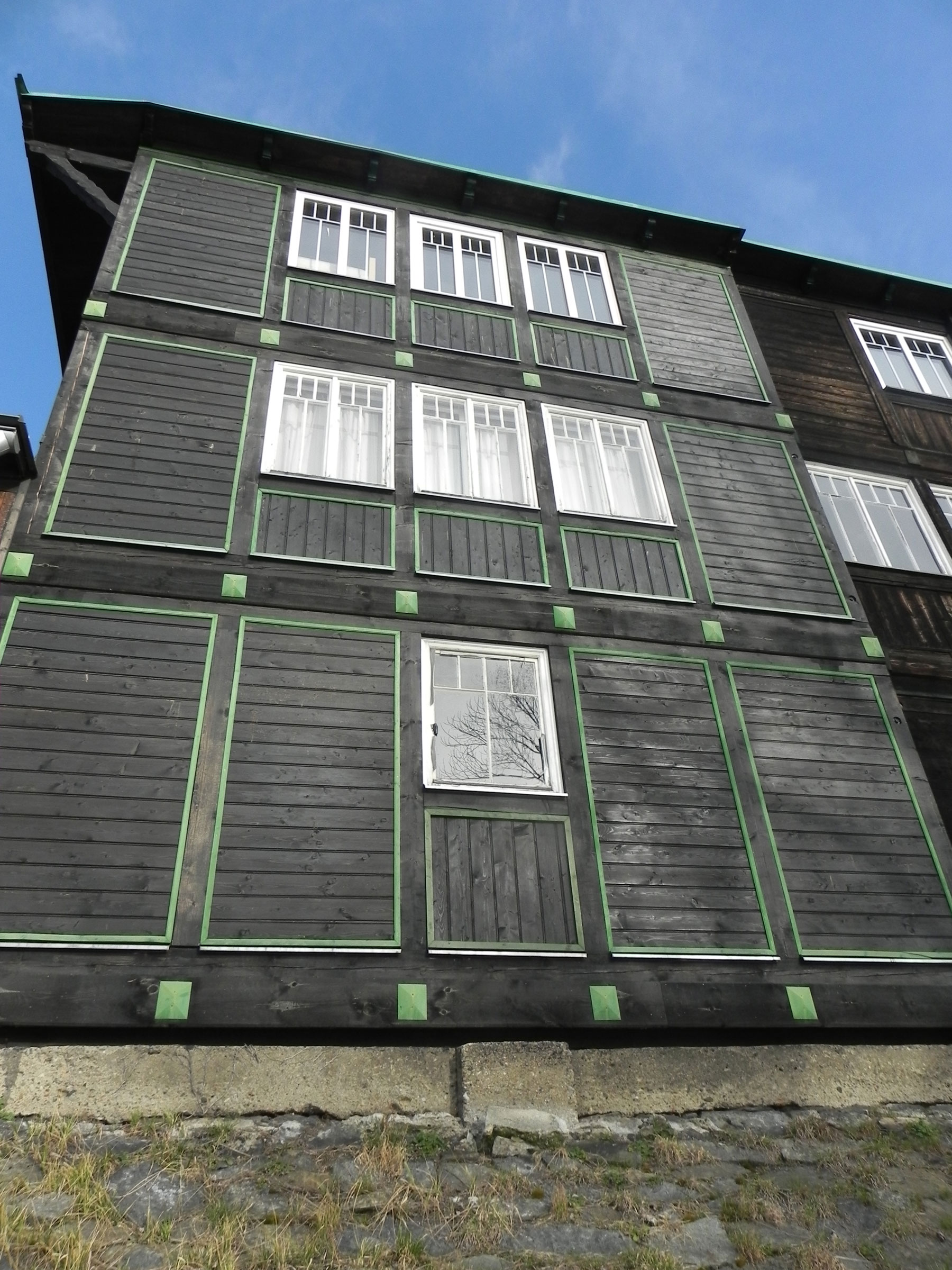 Výzdoba fasády je jednoduchá dřevěná. Plasticky soustružené dřevěné zelené kostky spolu se zelenými laťkami tmavou hladkou fasádu dynamizují a dávají jí punc začátku 20. století.