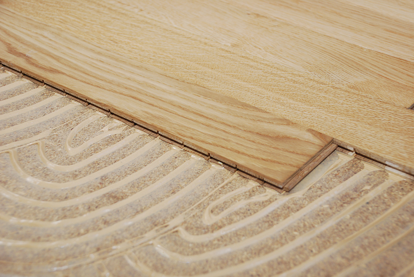 Detail aplikace lepidla na dřevěné podlahy