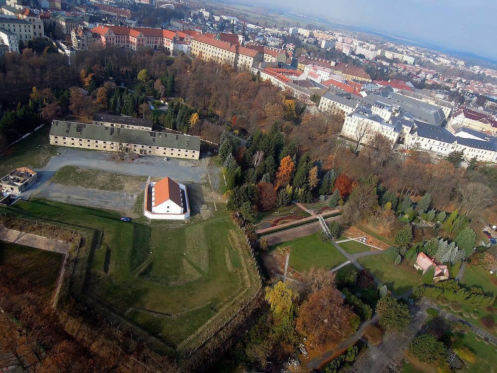 Objekt Velkého dělostřeleckého skladu v areálu na fotografii zachycující stav před započetím rekonstrukčních prací a na schématu areálu.