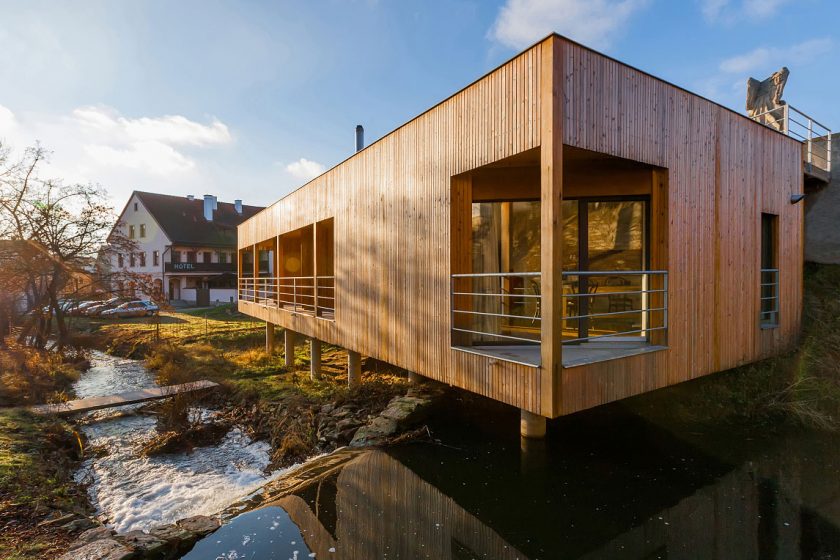 Dřevěný dům se zelenou střechou a vodopádem
